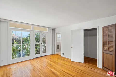 a view of empty room with wooden floor and fan