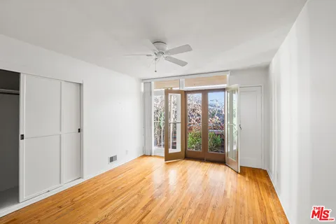 a view of empty room with wooden floor and fan