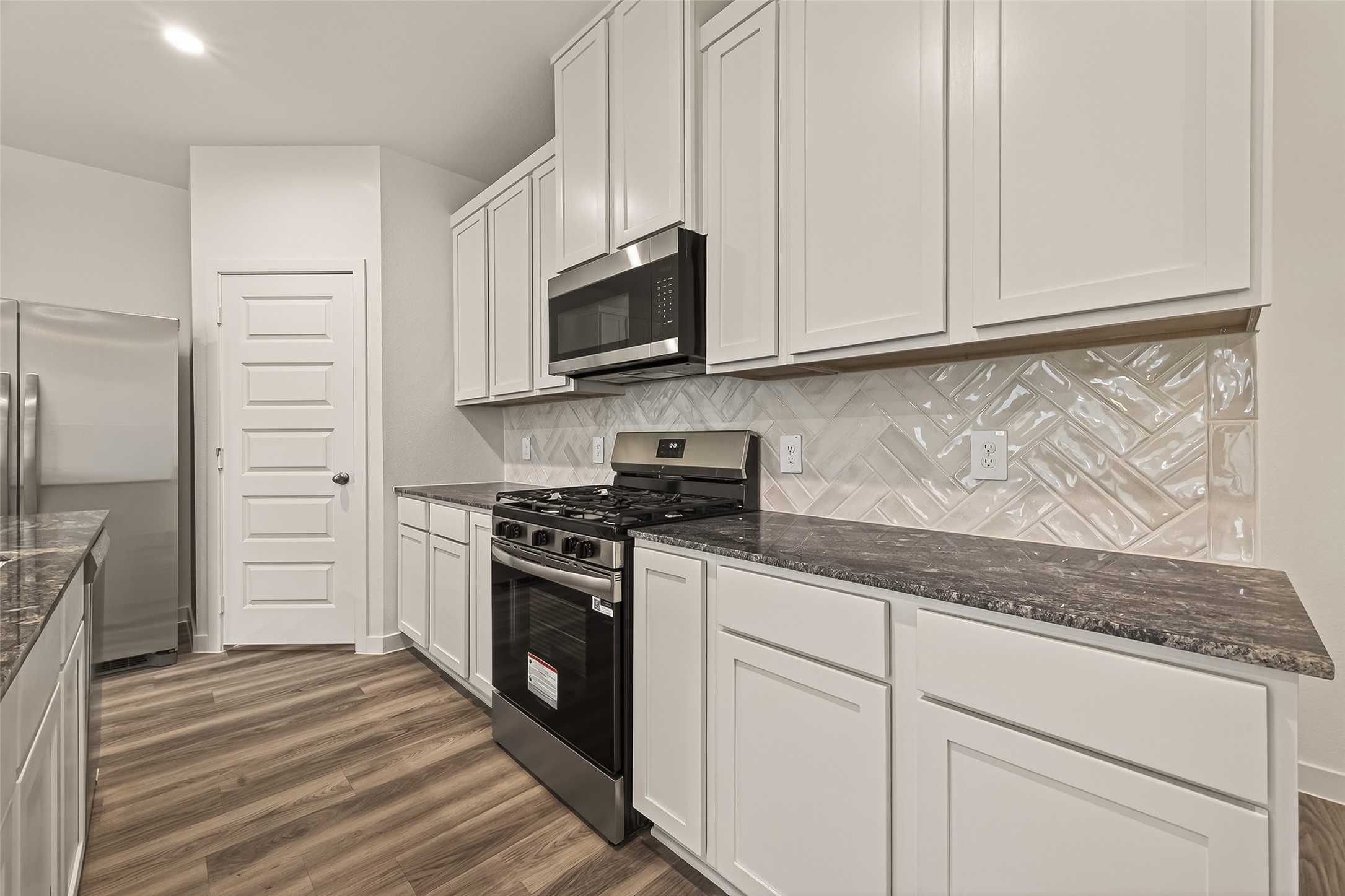 2826 Lisburn Ter Lane Houston, TX 77051 - Photo 4 of 18 a kitchen with stainless steel appliances granite countertop white cabinets and a stove a oven with wooden floor