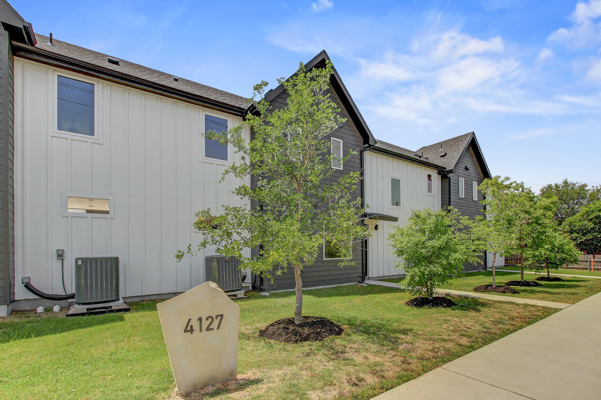 4127 East 12th Street, Unit 4 Austin, TX 78721 - Photo 32 of 32 View of side of property featuring board and batten siding, cooling unit, and a lawn