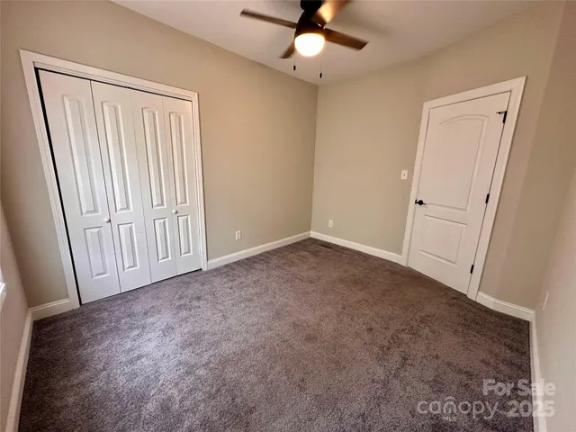 an empty room with windows and ceiling fan
