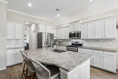 a kitchen with stainless steel appliances granite countertop a kitchen island hardwood floor sink and stove