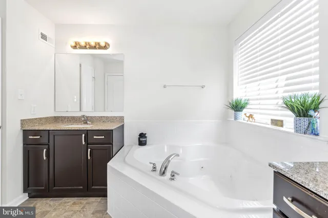 a bathroom with a granite countertop sink and a bathtub