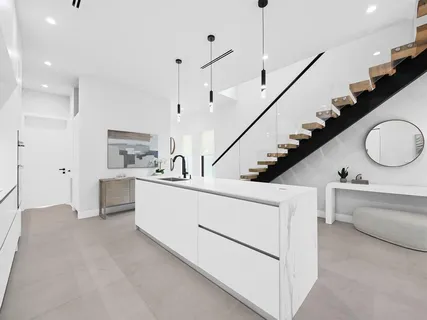 a large white kitchen with sink and stainless steel appliances