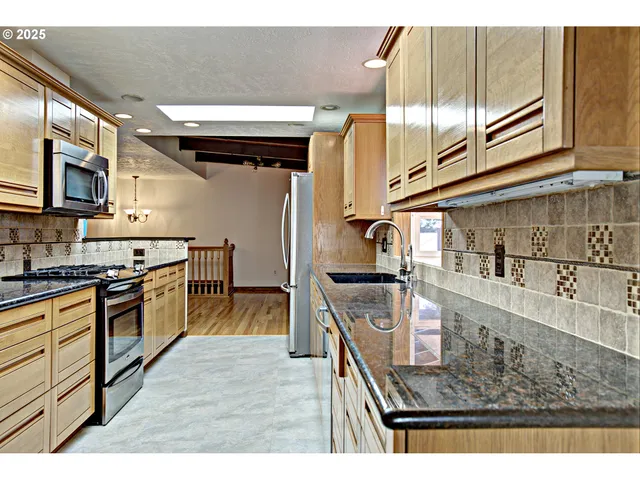a kitchen with stainless steel appliances granite countertop a stove a sink and a microwave