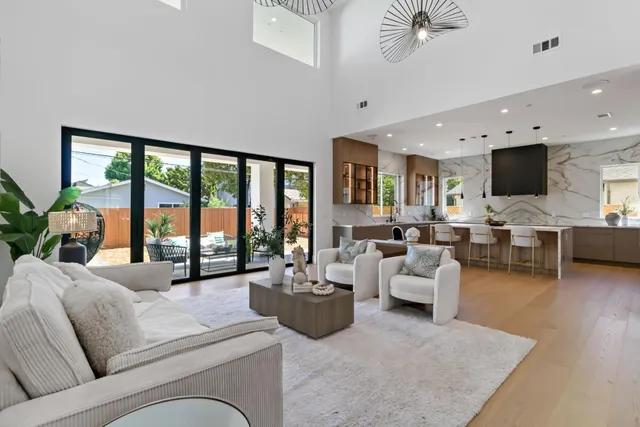 a living room with furniture kitchen view and a chandelier
