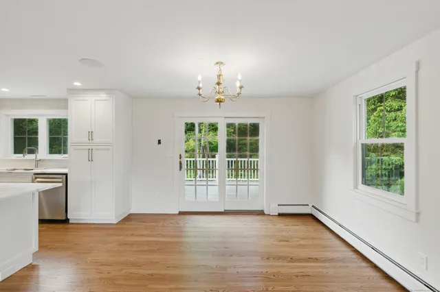 an empty room with wooden floor chandelier and windows