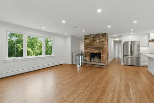 an empty room with wooden floor fireplace and windows