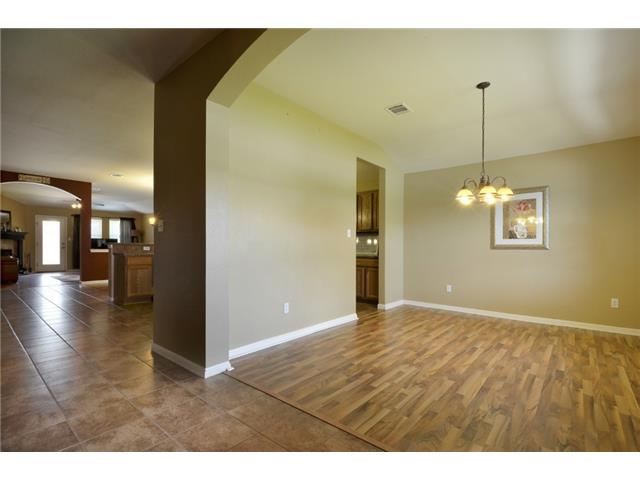 11612 Timber Heights Drive Austin, TX 78754 - Photo 12 of 28 Warm wood flooring extends into a spacious dining area, illuminated by a classic chandelier.
