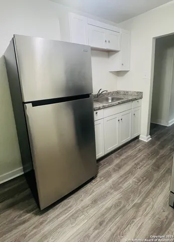 a kitchen with a refrigerator and white cabinets