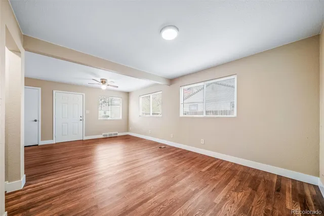 an empty room with wooden floor and windows