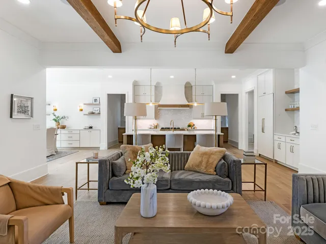 a living room with furniture kitchen view and a chandelier