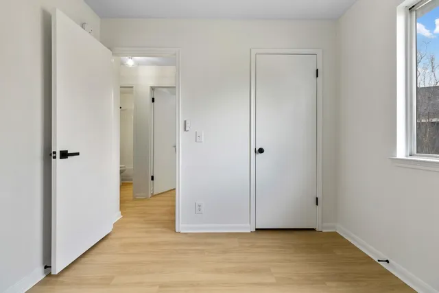 a view of a hallway with wooden floor and a bathroom