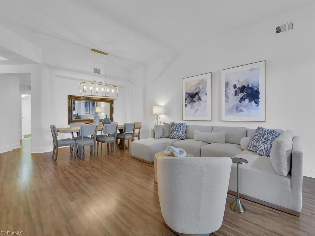 2710 Callista Court, Unit 104 Naples, FL 34114 - Photo 11 of 43 Living area featuring wood finished floors, baseboards, a chandelier, and visible vents