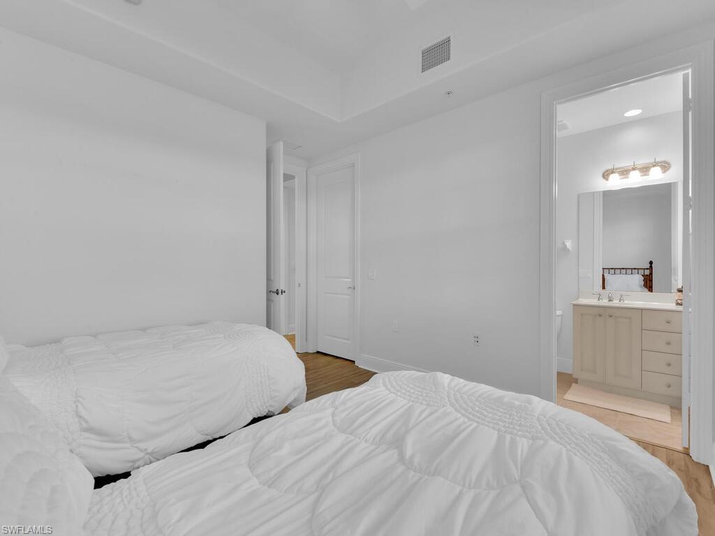 2710 Callista Court, Unit 104 Naples, FL 34114 - Photo 19 of 43 Bedroom featuring ensuite bathroom, baseboards, light wood-style flooring, and visible vents