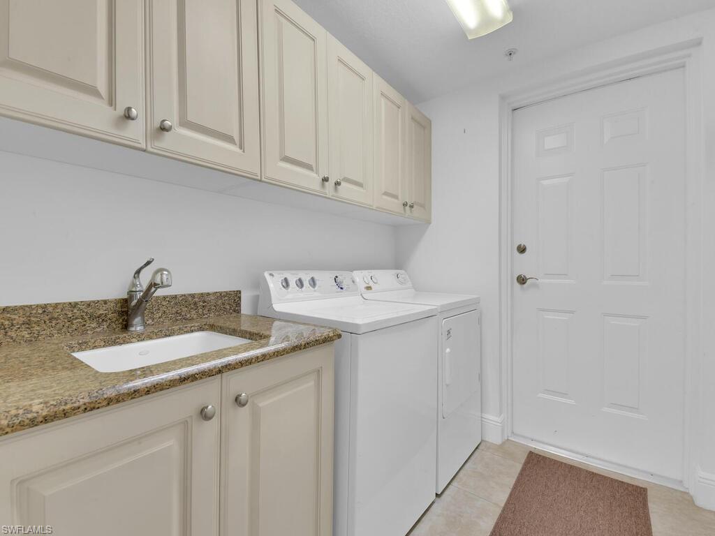 2710 Callista Court, Unit 104 Naples, FL 34114 - Photo 31 of 43 Washroom with light tile patterned floors, a sink, cabinet space, and washing machine and dryer
