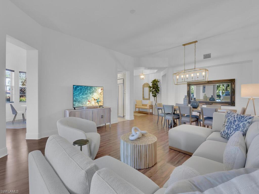 2710 Callista Court, Unit 104 Naples, FL 34114 - Photo 10 of 43 Living area featuring baseboards, visible vents, wood finished floors, and a chandelier