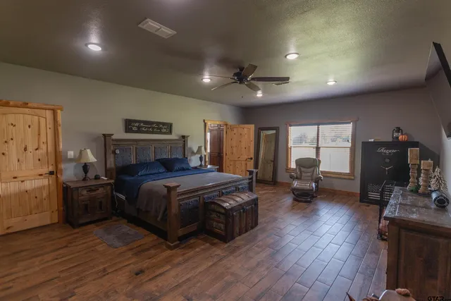 a spacious bedroom with a bed a table and wooden floor