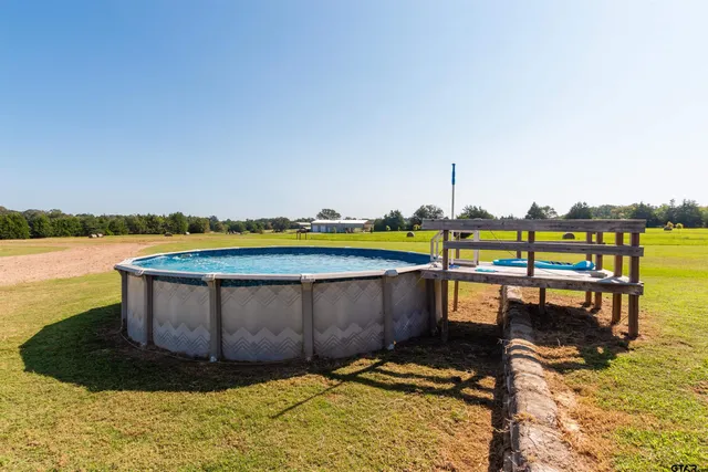a view of a swimming pool with lawn chairs and a yard
