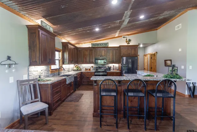 a kitchen with lots of wooden furniture appliances and dining table