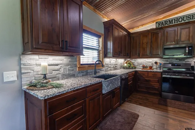 a kitchen with stainless steel appliances granite countertop wooden cabinets a stove top oven a sink and dishwasher