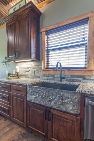 a kitchen with granite countertop wooden cabinets a sink and dishwasher next to a window