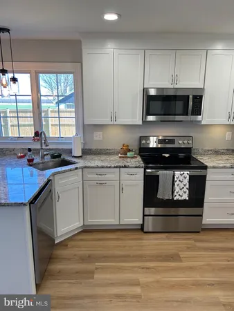 a kitchen with stainless steel appliances granite countertop a stove a sink dishwasher and a microwave oven with wooden cabinets