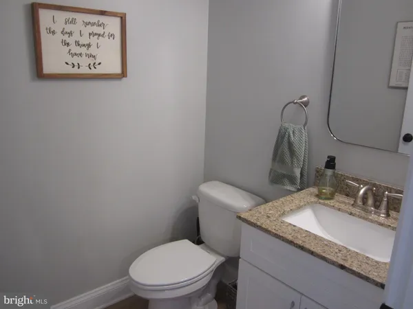 a bathroom with a granite countertop toilet sink and mirror