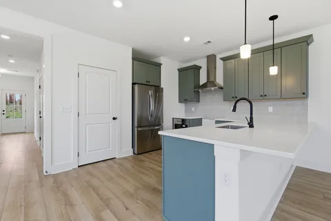 a kitchen with stainless steel appliances a sink a refrigerator a center island and wooden floor