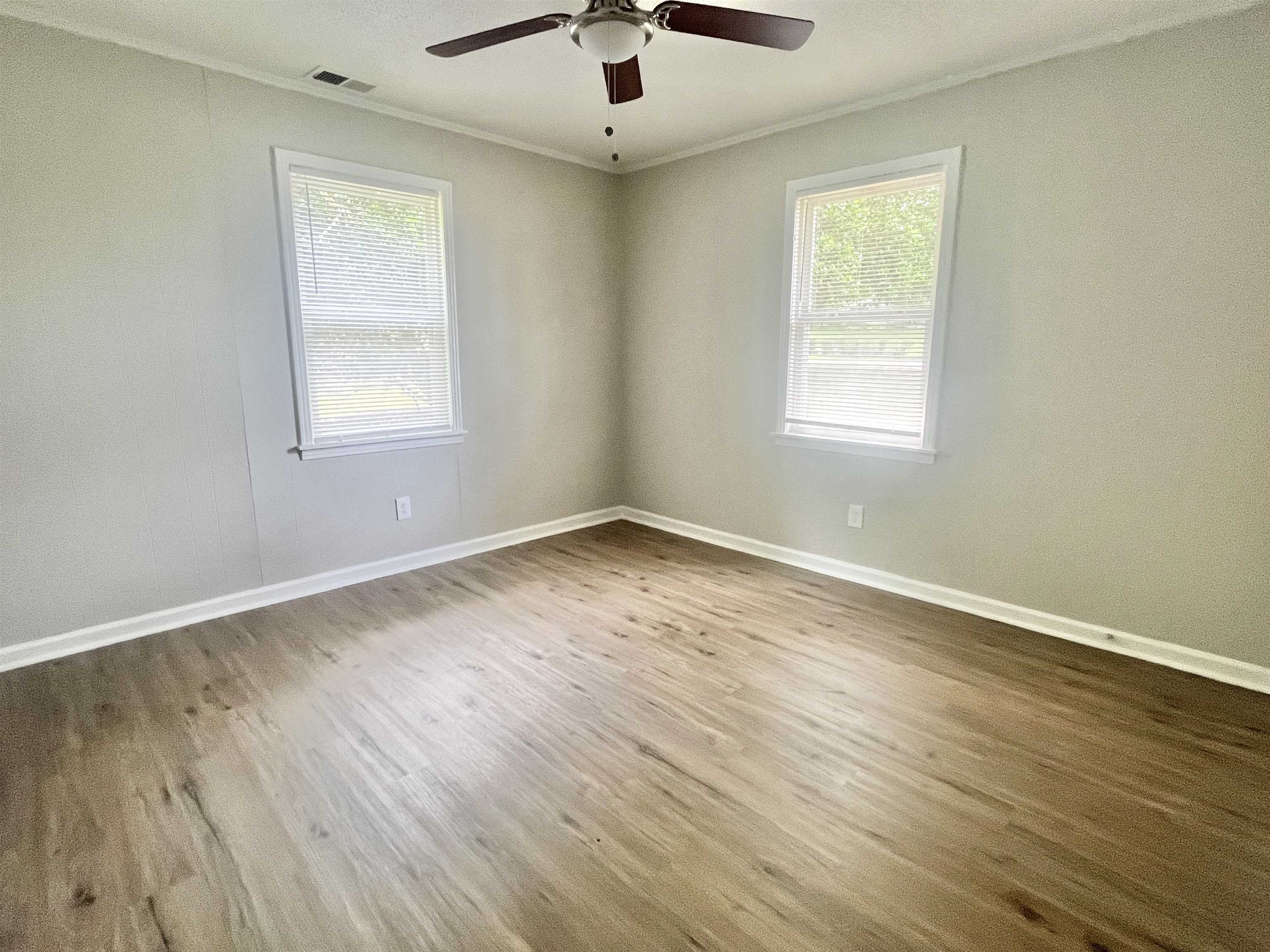 1172 Tabernacle Road Covington, TN 38019 - Photo 9 of 13 an empty room with wooden floor chandelier fan and windows