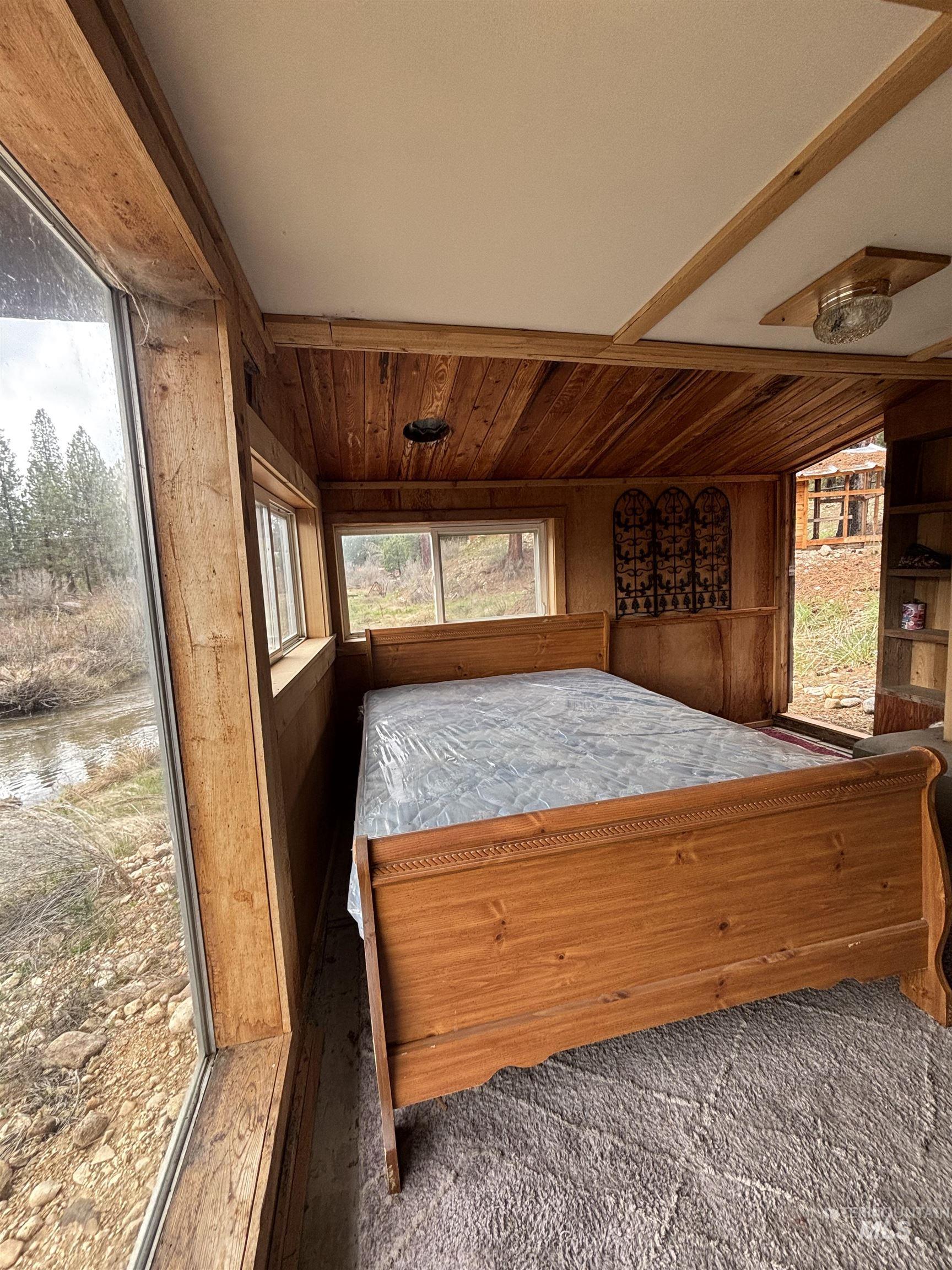 29 McIntyre Gulch Road Boise, ID 83716 - Photo 21 of 50 Wood-paneled room featuring a sloped wood-finish ceiling, exposed wood beams, and a large window overlooking a natural landscape
