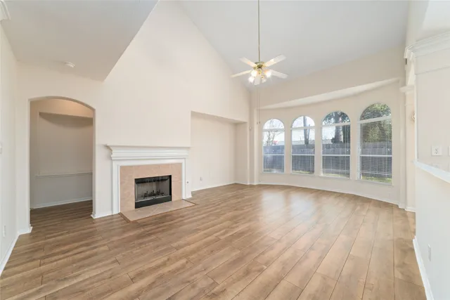 an empty room with wooden floor fan and windows