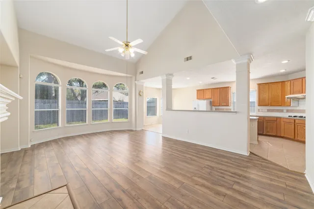 a view of an empty room with a kitchen and wooden floor