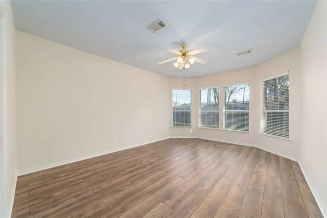 a view of an empty room with a window and wooden floor