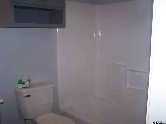 a white toilet sitting next to a shower