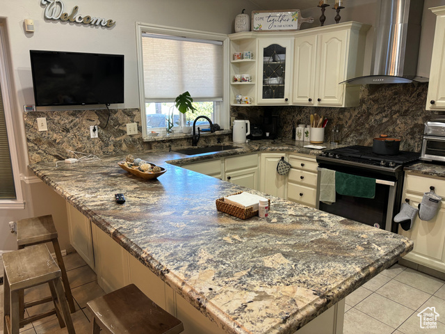 1874 South Main Street Orem, UT 84058 - Photo 3 of 15 Kitchen featuring wall chimney exhaust hood, backsplash, dark stone counters, and stainless steel gas range oven