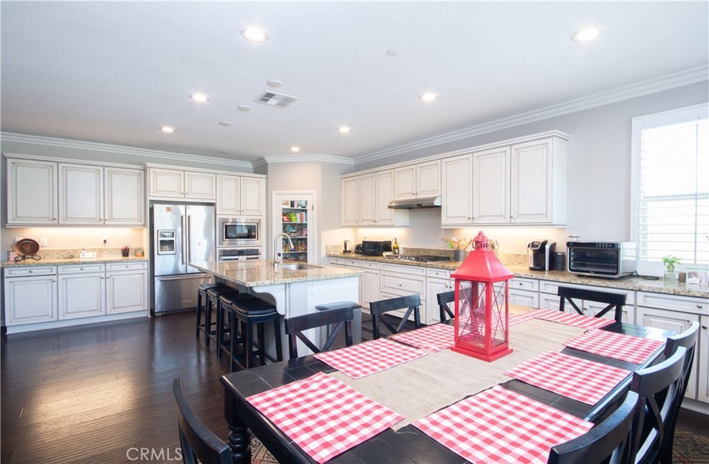11950 Flicker Cove Corona, CA 92883 - Photo 5 of 28 an open kitchen with dining table and chairs