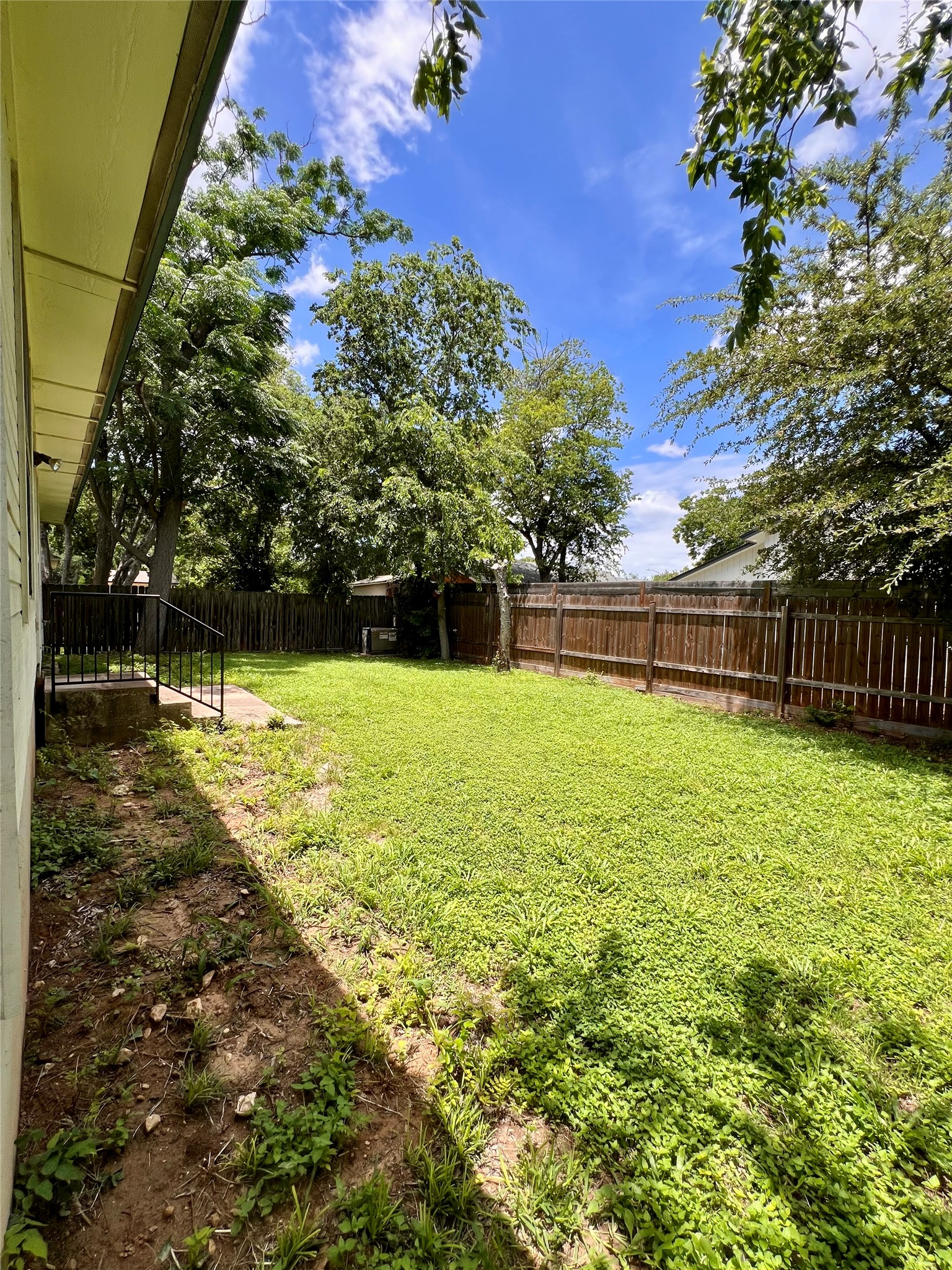 5404 China Berry Road Austin, TX 78744 - Photo 19 of 20 A secluded backyard sanctuary features a well-maintained lawn, privacy fencing, and mature shade trees.