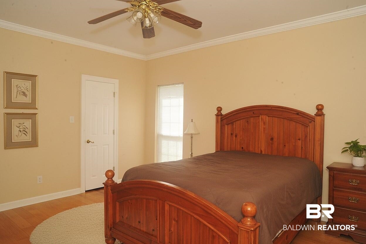 8008 Patricks Landing Road Bay Minette, AL 36507 - Photo 21 of 33 Hardwood-style flooring extends throughout this room, featuring crown molding, a ceiling fan with integrated lighting, and a window with blinds