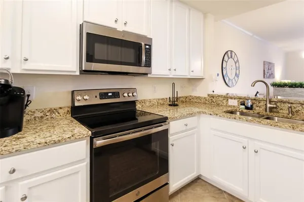 a kitchen with granite countertop white cabinets and stainless steel appliances