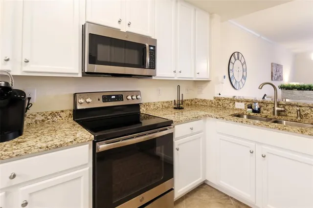 a kitchen with granite countertop white cabinets and stainless steel appliances