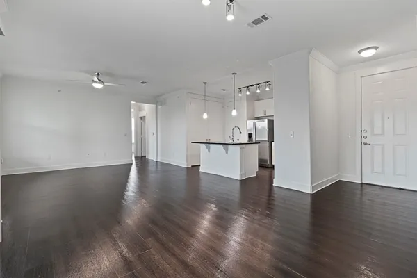 a view of a kitchen and an empty room with wooden floor