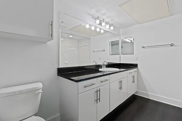 a bathroom with a granite countertop sink a toilet and a mirror