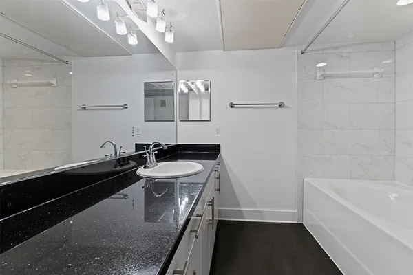 a bathroom with a sink a large mirror and a bathtub
