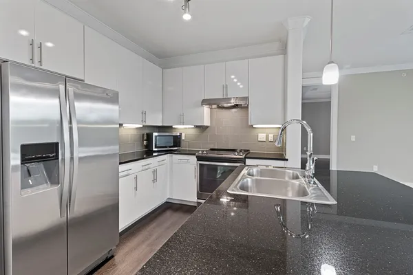 a kitchen that has a lot of cabinets and stainless steel appliances