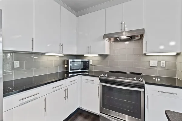 a kitchen with granite countertop white cabinets and white appliances