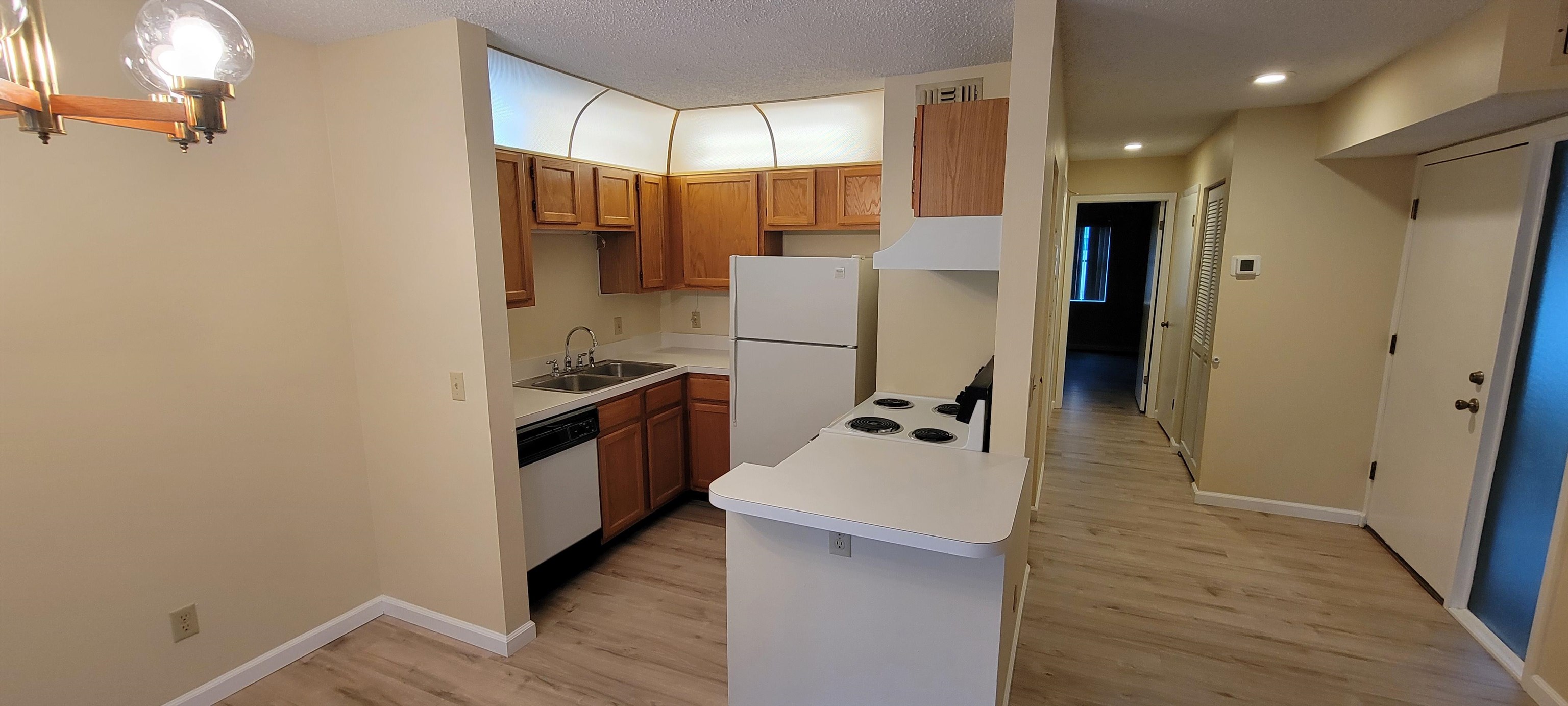 5 Catalonia Court St. Augustine, FL 32086 - Photo 6 of 30 Kitchen with wood finish cabinets, light countertops, white appliances, light wood-style floors, and a textured ceiling