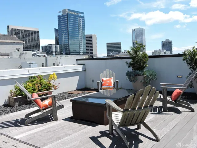 a view of a patio with couches and a table and chairs with wooden floor and fence