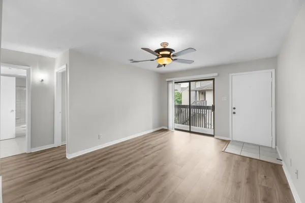 a view of an empty room with a window and wooden floor