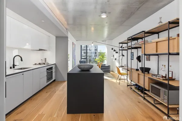 a kitchen with stainless steel appliances granite countertop a refrigerator a sink dishwasher a stove and white countertops with wooden floor